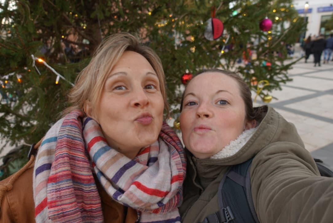 two people kissing in front of a christmas tree