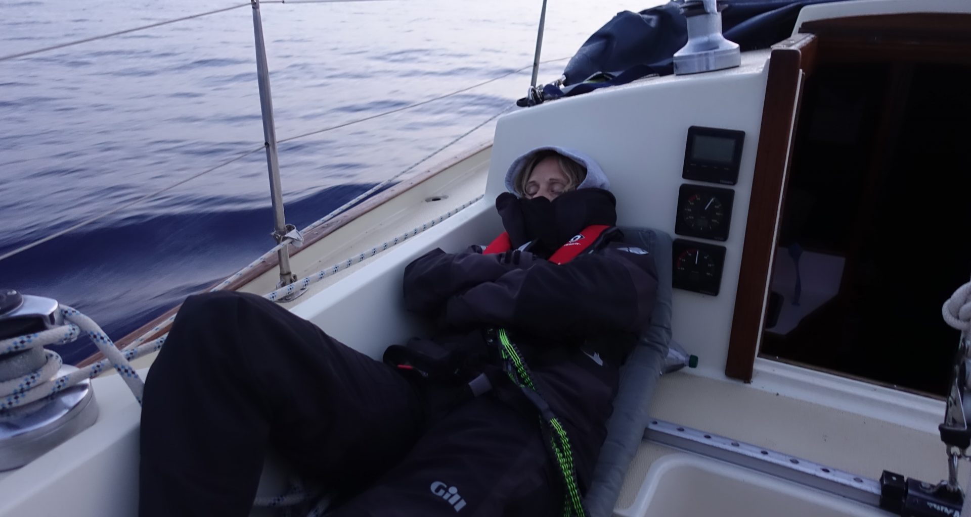 person sleeping in a cockpit of a sailing boat