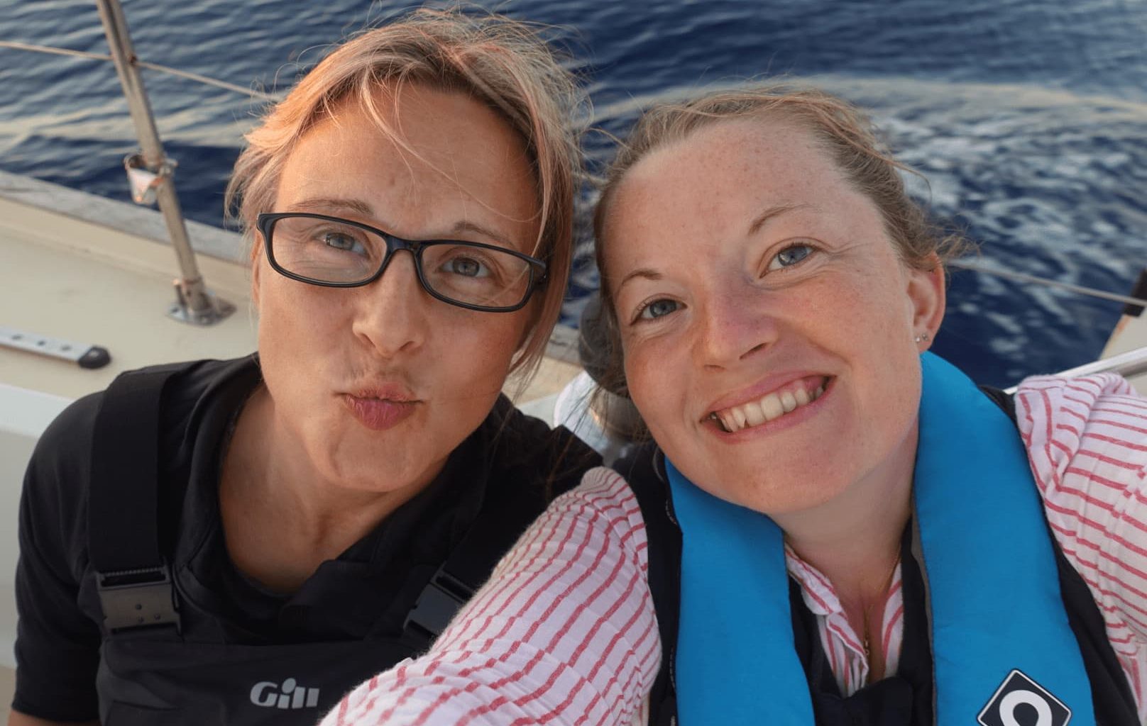 two sailors in lifejackets on a sailing boat passage