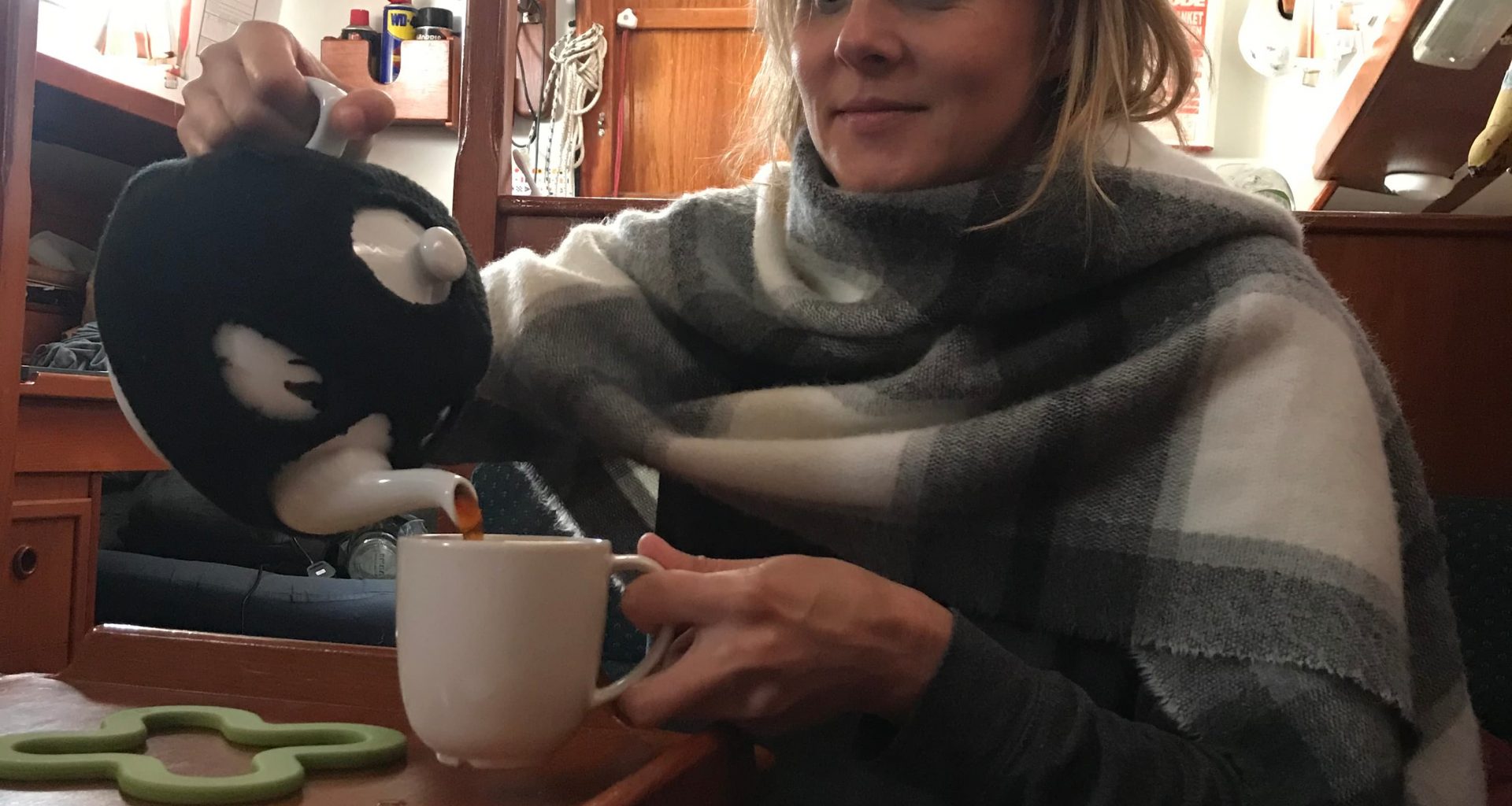 person pouring tea from a teapot on a boat