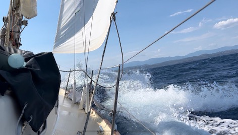 sailing boat crashing through waves