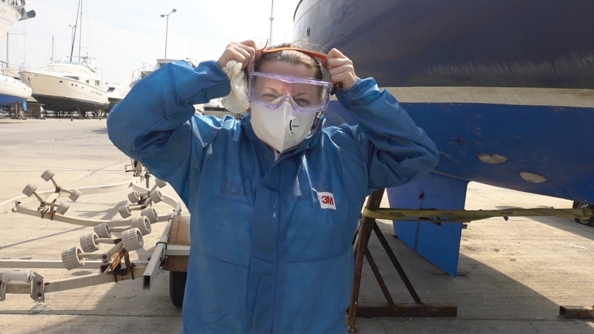 girl with a mask and overalls on in a boatyard
